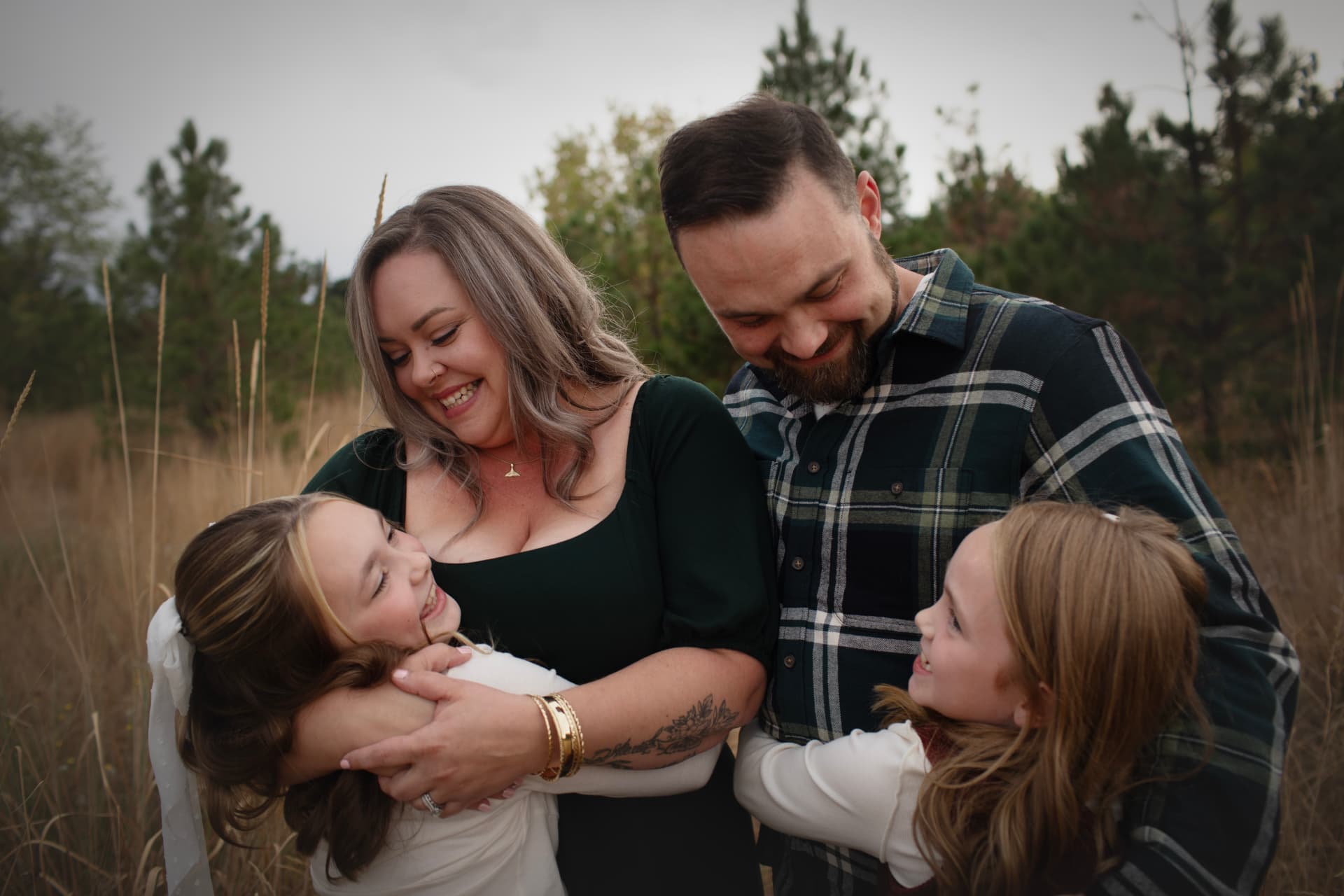 Parents laughing with their daughters in a tall-grass field