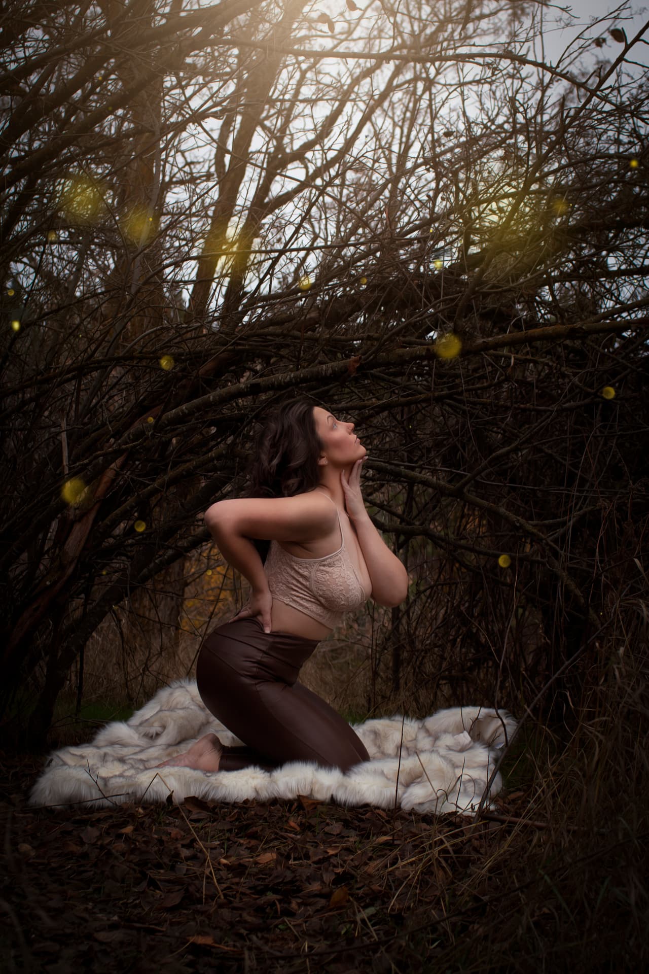Woman kneeling on a fur rug in a forest at golden hour
