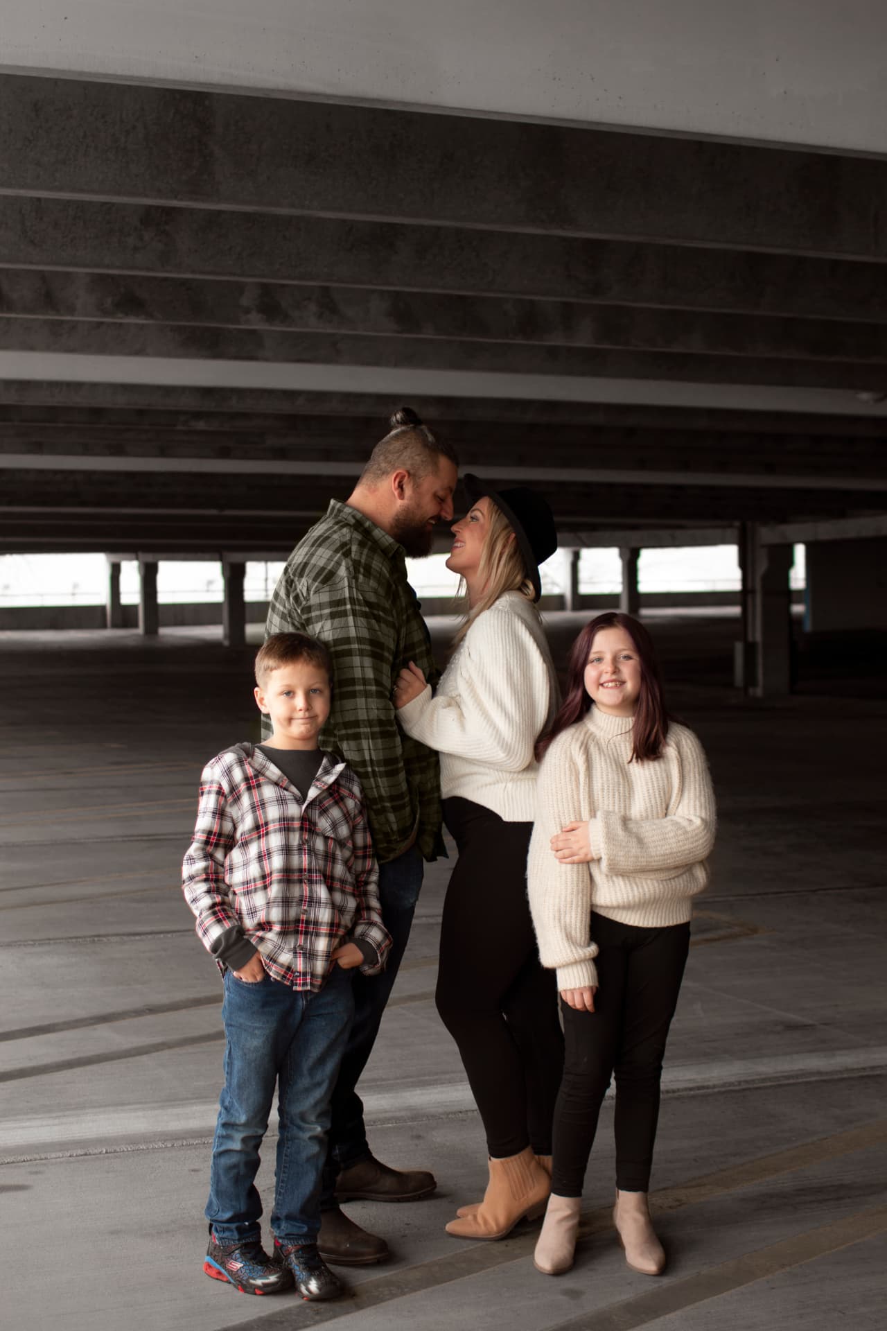 Parents sharing a kiss with their kids in a parking garage